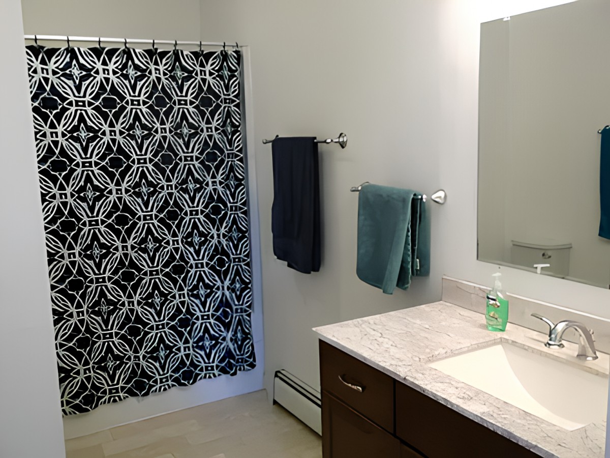 A modern bathroom with a patterned shower curtain and neatly arranged towels.