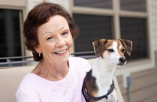 A smiling woman enjoys a sunny day with her dog.