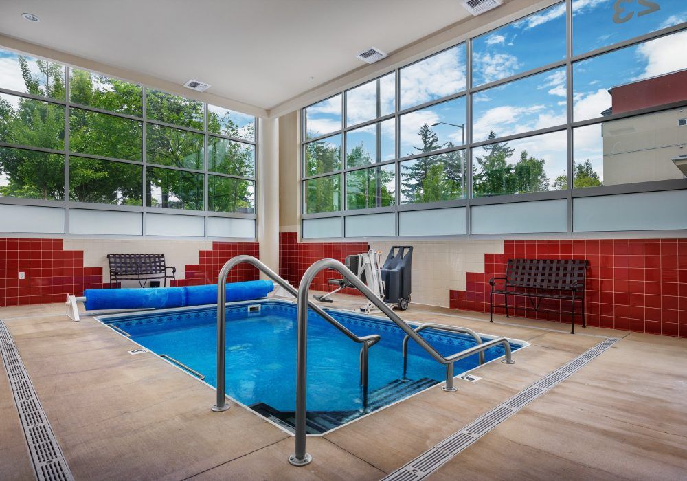 A modern indoor swimming pool with large windows and seating areas.