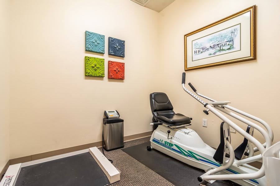 A small exercise room with a stationary bike and colorful artwork on the wall.