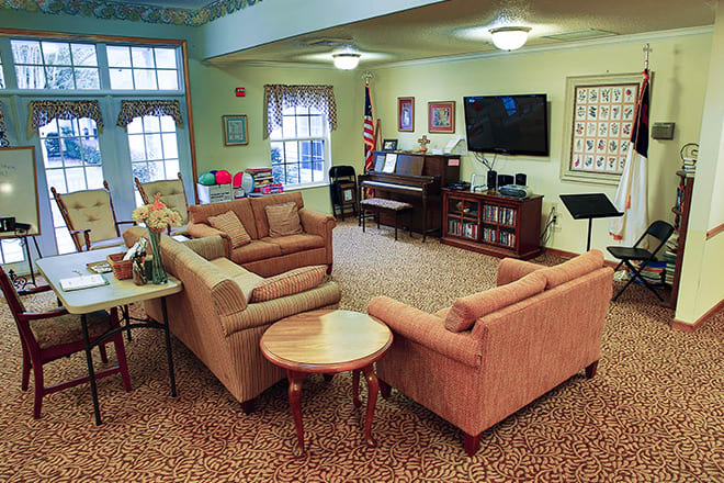 A cozy living room with sofas, a piano, and a television.
