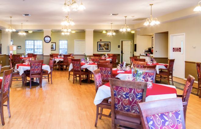 A well-decorated dining room with arranged tables and chairs, featuring warm lighting.