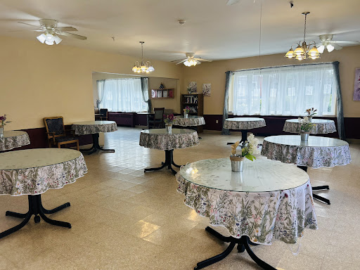 A spacious and well-lit dining area featuring tables adorned with floral tablecloths, ready for guests.