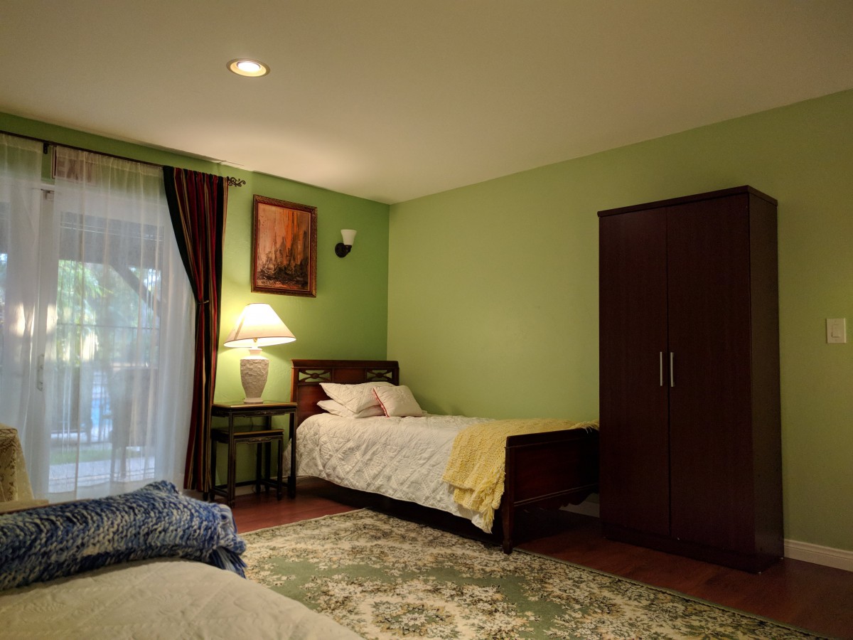 A cozy bedroom with a single bed, wardrobe, and warm lighting.