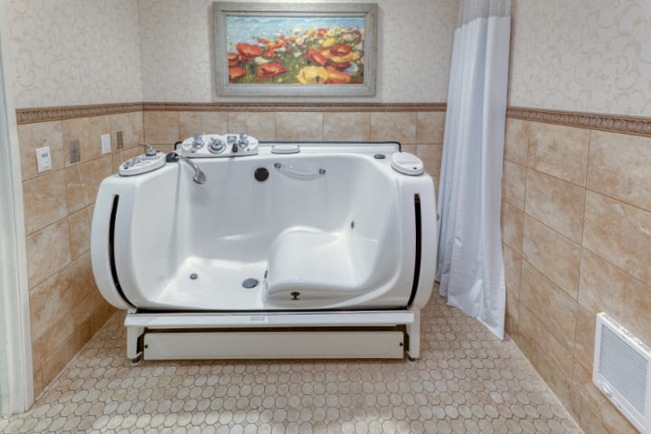 A modern bathroom featuring a high-tech bathtub with tile flooring and decorative artwork.