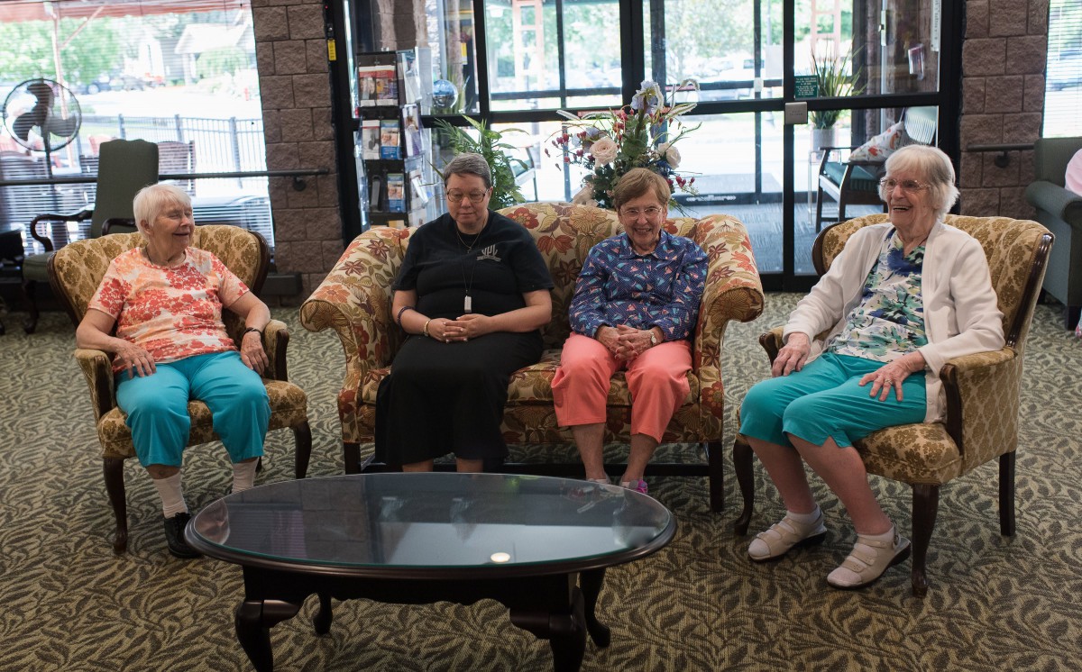 A group of people sitting on sofas in a well-lit indoor setting.