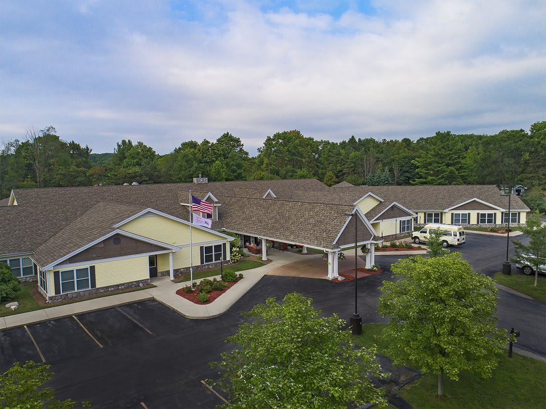 Aerial view of a residential building with a parking lot surrounded by trees.