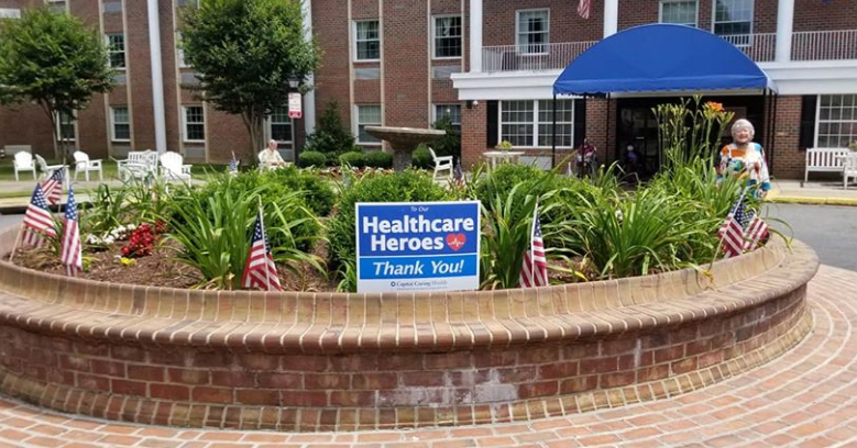 A thank you sign for healthcare heroes displayed in front of a building, surrounded by small American flags and greenery.