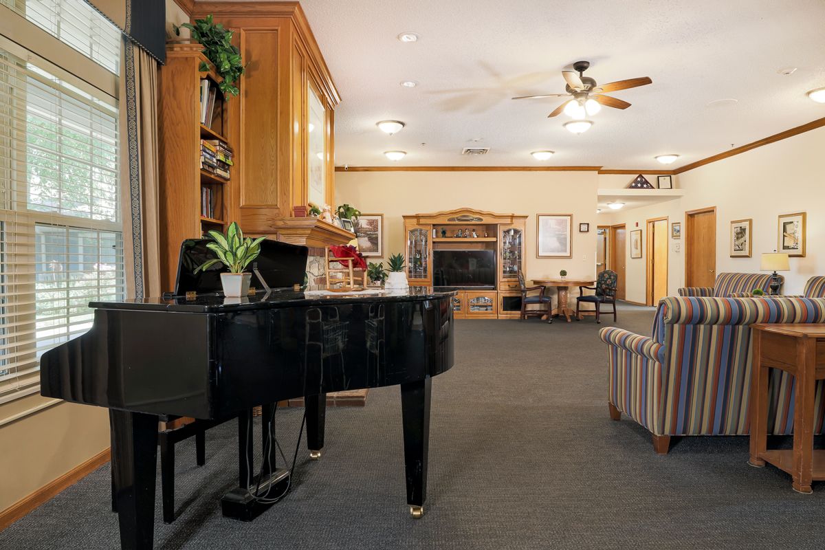 A cozy living room with a grand piano, bookshelf, and comfortable seating.