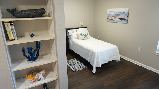 A cozy and minimalist bedroom featuring a single bed with white bedding, decorative pillows, and a stylish shelf.