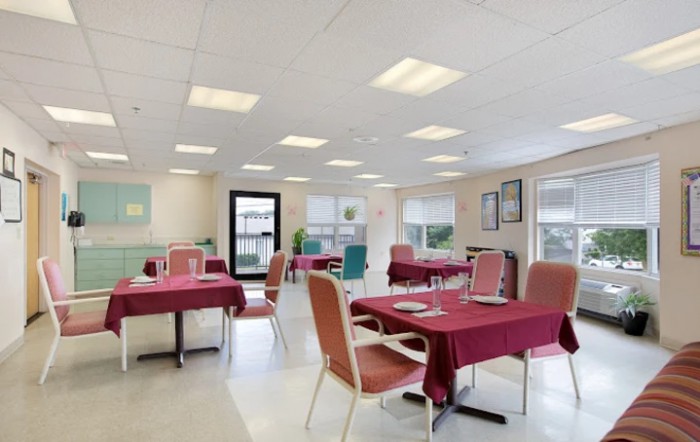 An empty dining room with tables and chairs covered in red tablecloths.