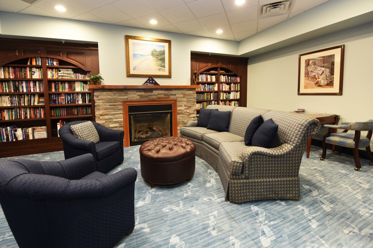 A cozy reading room with a fireplace, sofa, and bookshelves.