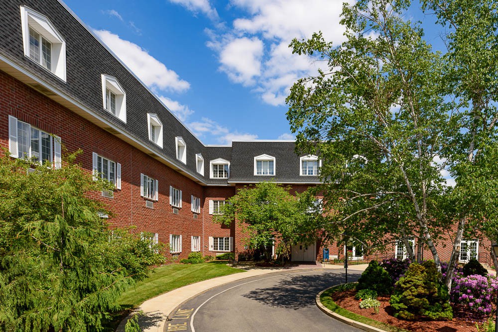 A brick building with a landscaped driveway and a clear blue sky.