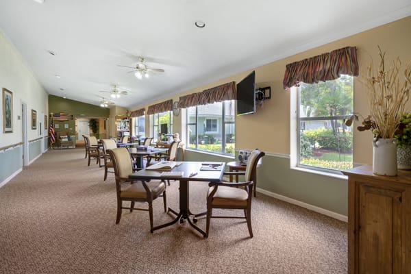 A spacious dining area with tables and chairs, filled with natural light from large windows.