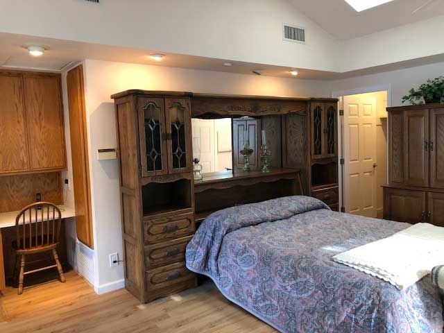 A cozy bedroom featuring a bed with wooden cabinets and a quilted bedspread.