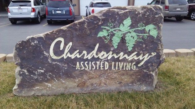 A stone sign for Chardonnay Assisted Living featuring a vineyard motif.