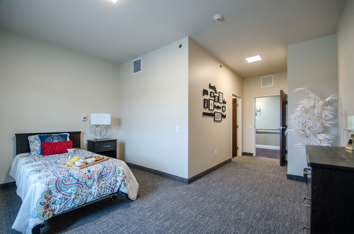 A spacious modern bedroom with simple decor and wall art.