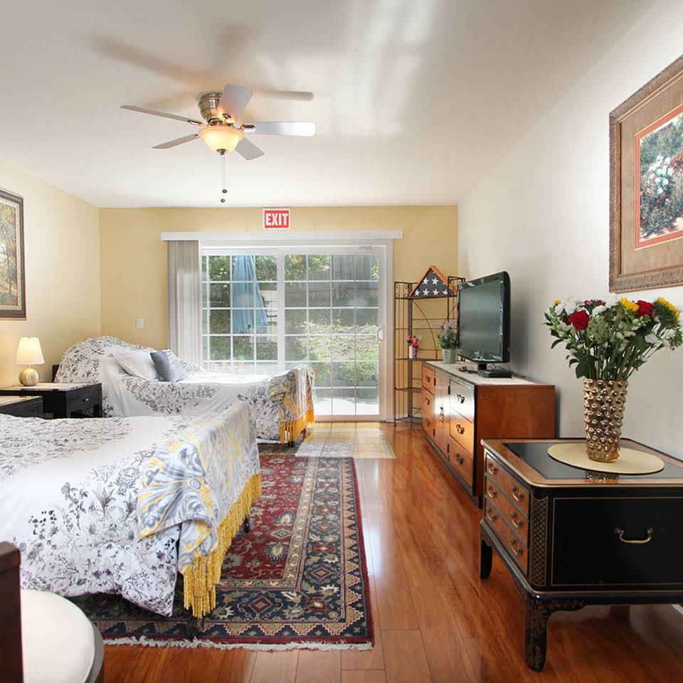 A cozy bedroom featuring a large bed, elegant decor, and a bright atmosphere with ample natural light streaming through the large sliding window.