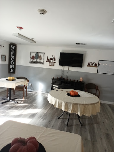 A welcoming interior space featuring round tables and a TV, designed for gatherings or meetings.