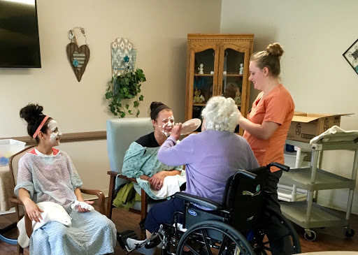 Caregivers engaging with elderly residents during a group activity in an assisted living facility.