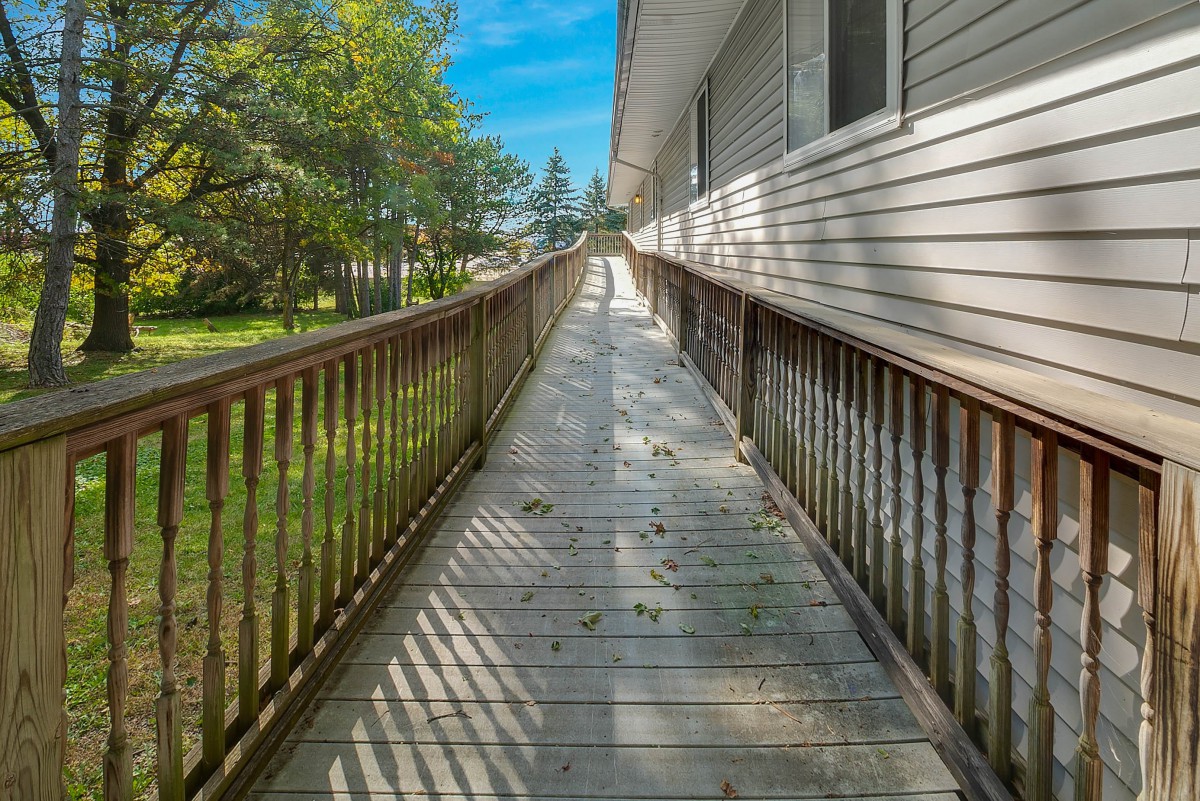 A long wooden ramp with handrails on a sunny day, casting shadows along the pathway.