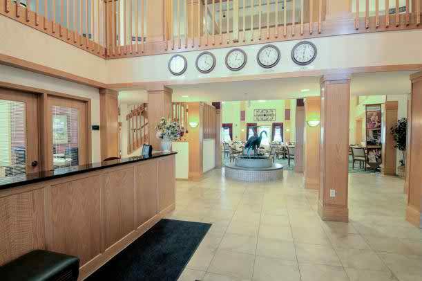 A modern hotel lobby with a reception desk and several clocks displaying different time zones.