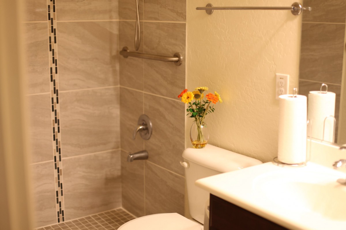 A modern bathroom with a walk-in shower and decorative flowers on the toilet.