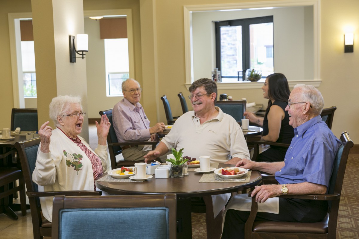 A group of seniors enjoying a meal and conversation at a community dining area.