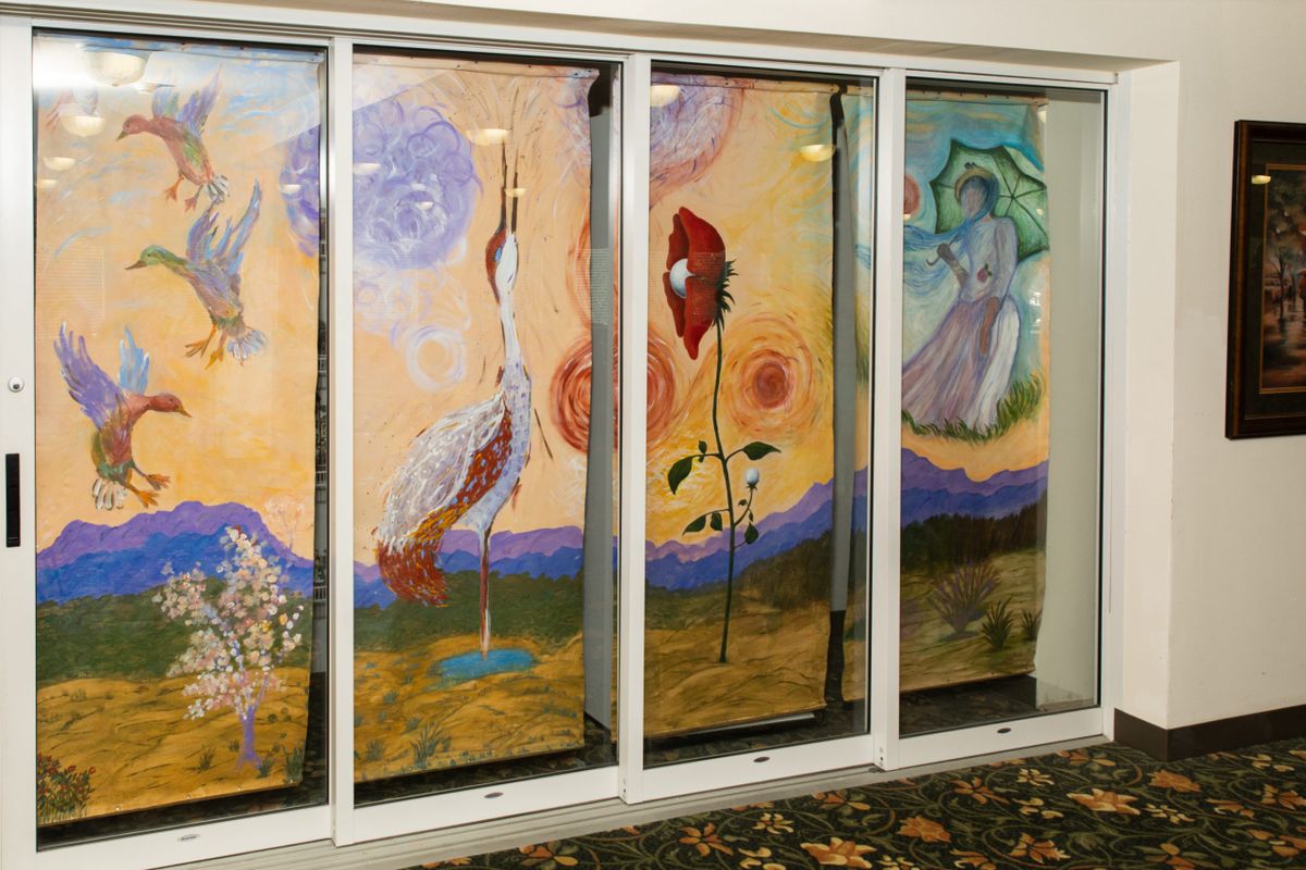 A vibrant stained glass window featuring abstract figures and floral elements.