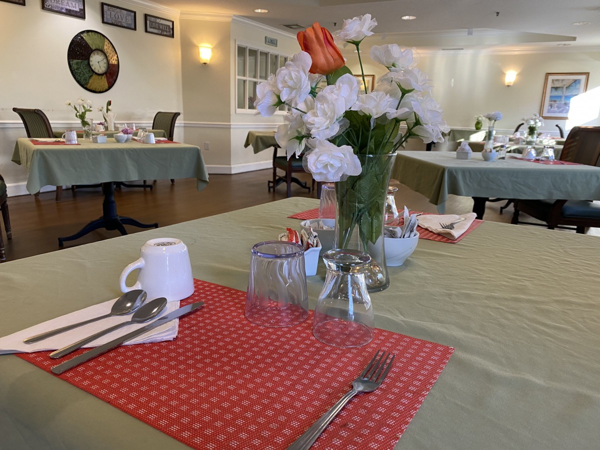 A dining table set with a vase of flowers and neatly arranged utensils in a restaurant.