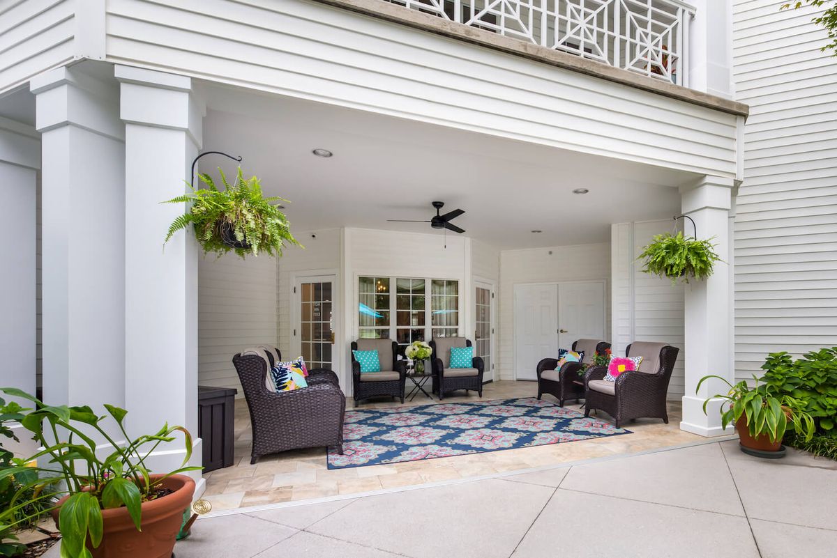 A cozy outdoor patio area with comfortable seating, plants, and a ceiling fan.