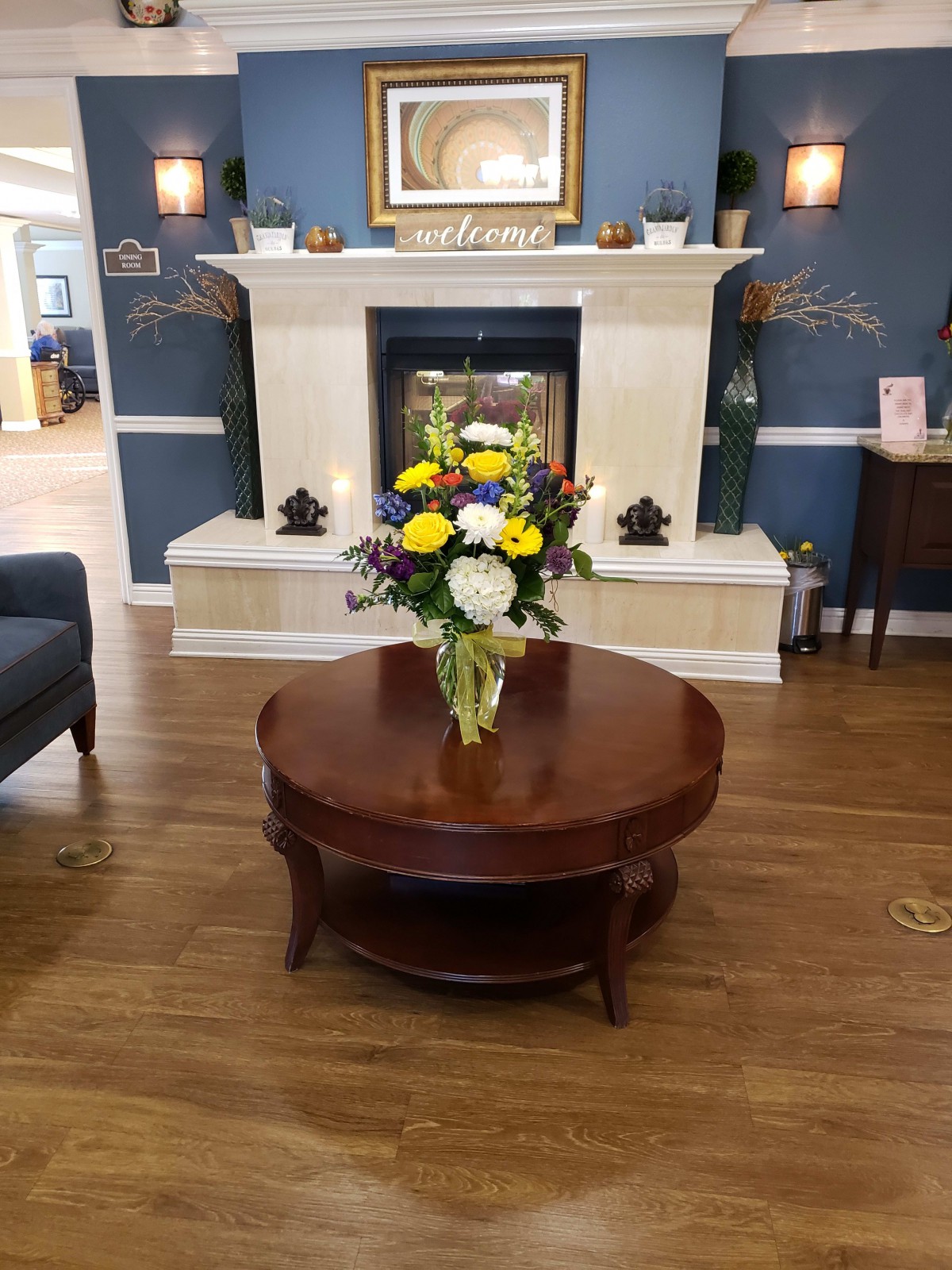 A cozy living room with a beautifully arranged flower bouquet on the coffee table in front of a fireplace.