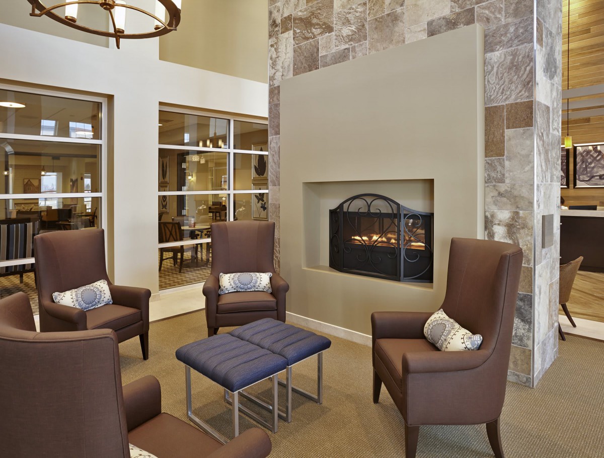 A modern lounge area with cozy seating arranged around a fireplace.