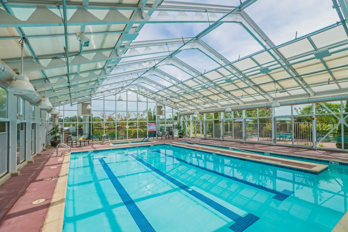 An indoor swimming pool with a spacious glass roof allowing natural light to fill the area.