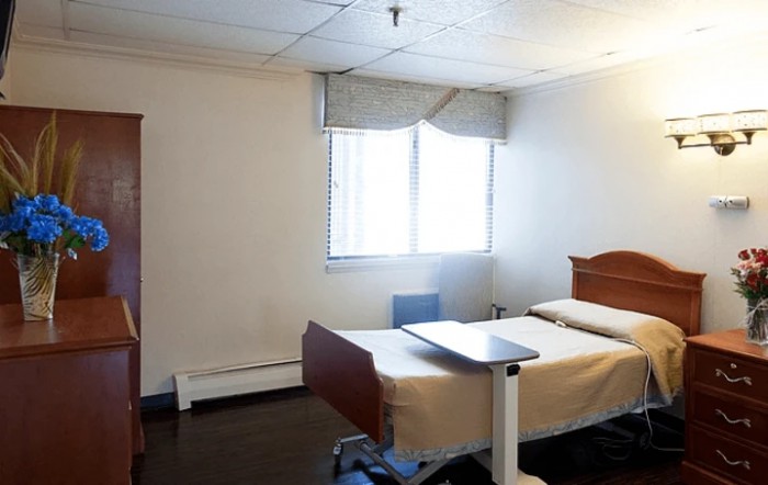A hospital room with a single bed and window.