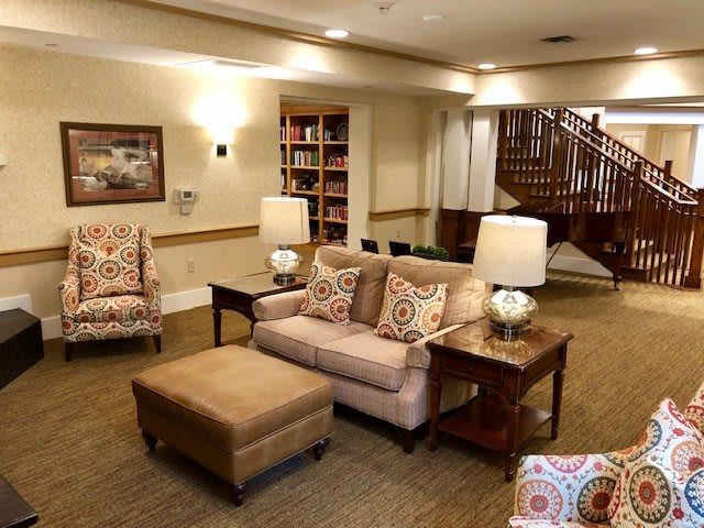 A cozy living room with comfortable seating, table lamps, and a bookshelf.