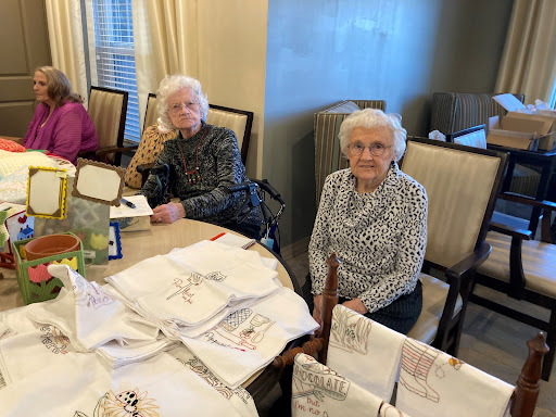 Two elderly women enjoying a crafting session at a communal table.