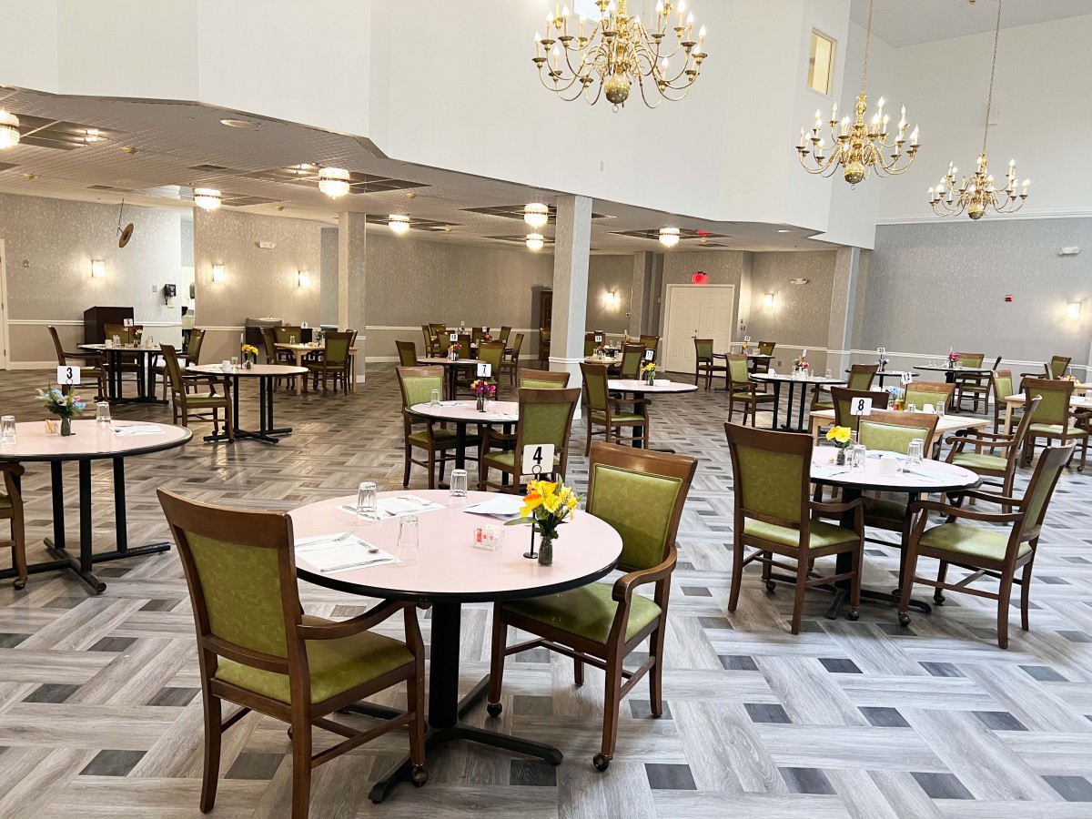 An empty dining area with multiple tables and chairs, decorated with chandeliers.