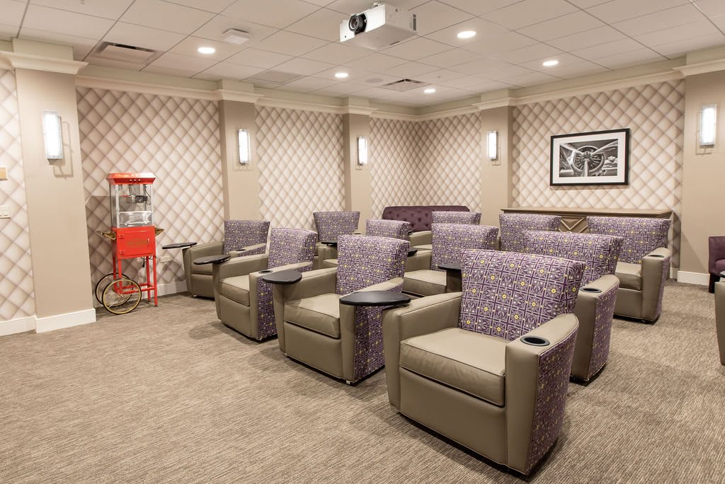 A cozy home theater room with plush seating and a popcorn machine for an enhanced movie-watching experience.