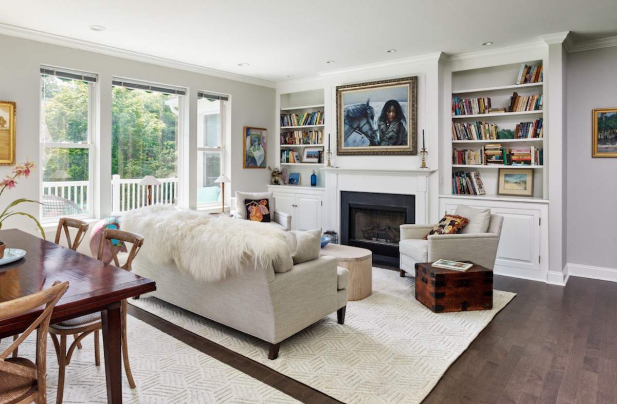 Cozy living room with a modern aesthetic, featuring a comfortable sofa, fireplace, and bookshelves filled with books, illuminated by natural light.