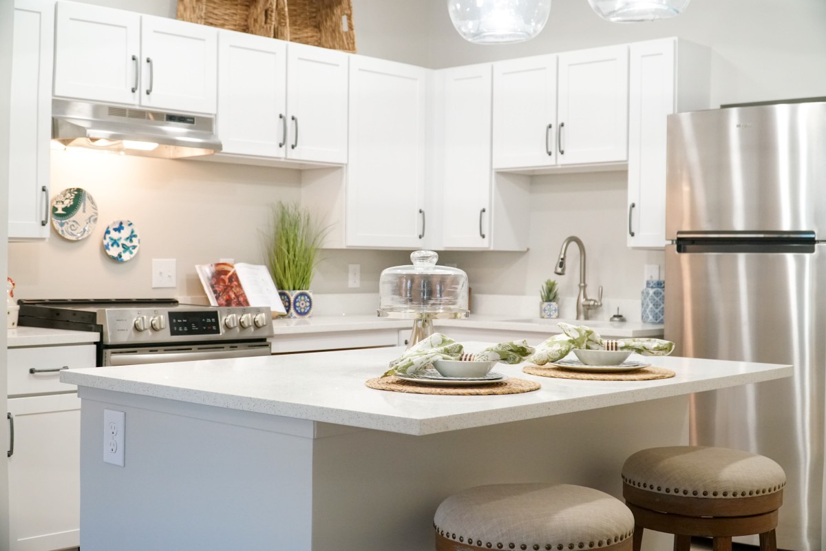 A modern kitchen with white cabinets and decorative items on the countertop.