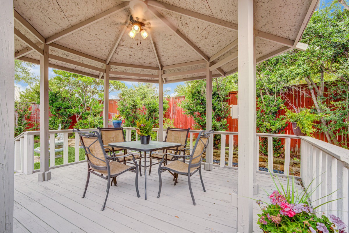 A charming gazebo with outdoor furniture set amidst a lush garden.
