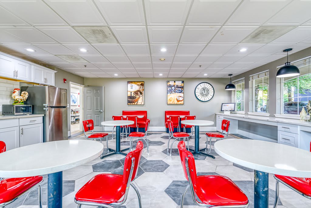 A retro-themed diner featuring red chairs and round tables in a classic vintage setting.