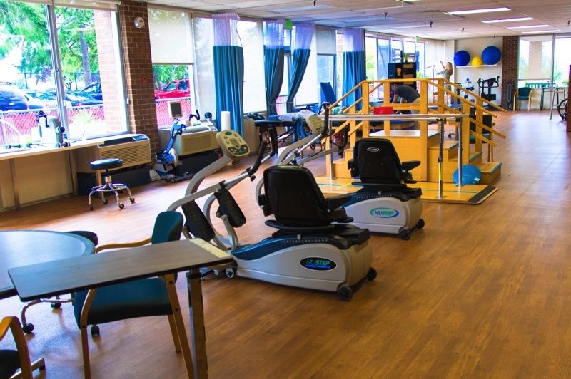 A rehabilitation center with various exercise equipment and therapy areas.