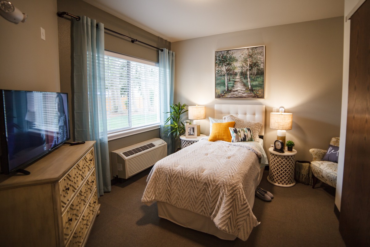 A cozy bedroom with a single bed, soft lighting, and warm decor.