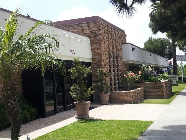 A modern building with brick detailing surrounded by lush landscaping and palm trees.