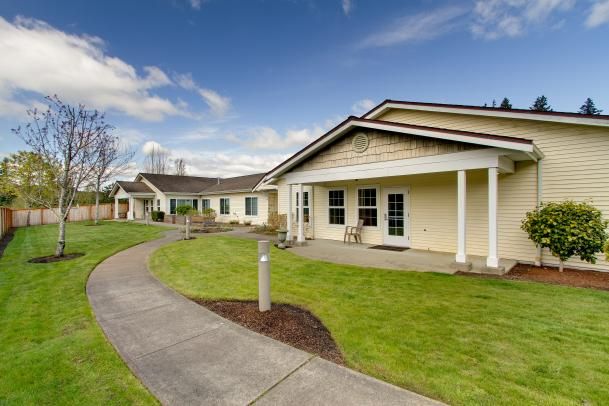 A scenic view of a modern residential building with a well-maintained lawn and pathway under a clear blue sky.