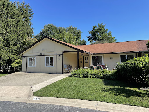 A charming single-story house with a well-maintained front yard and clear blue skies.