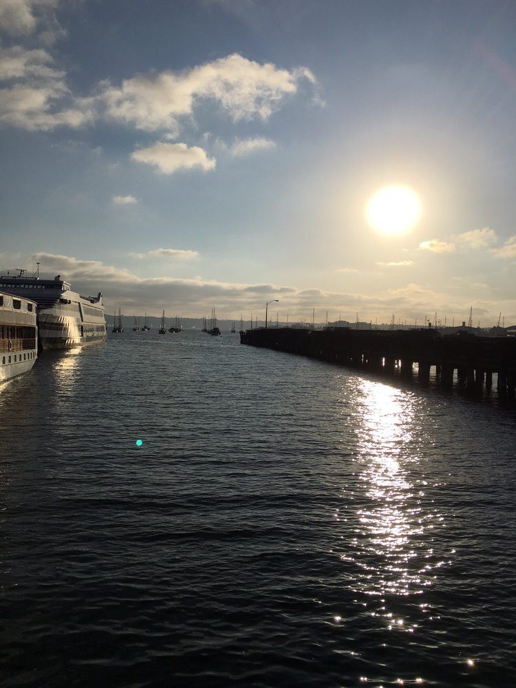 A serene sunset over a calm body of water, with boats docked near a pier.