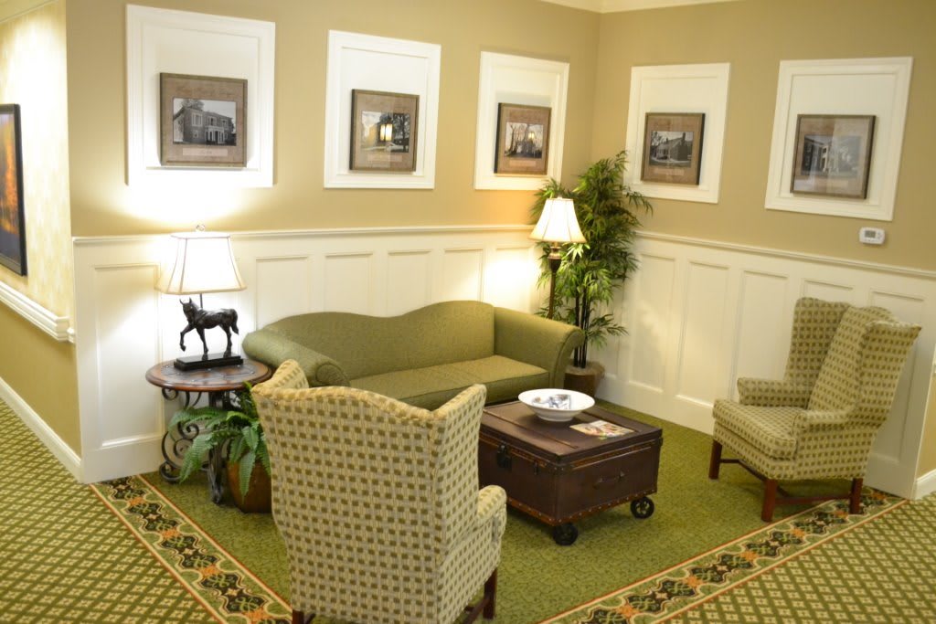 A cozy living room with a green sofa, armchairs, and decorative elements.
